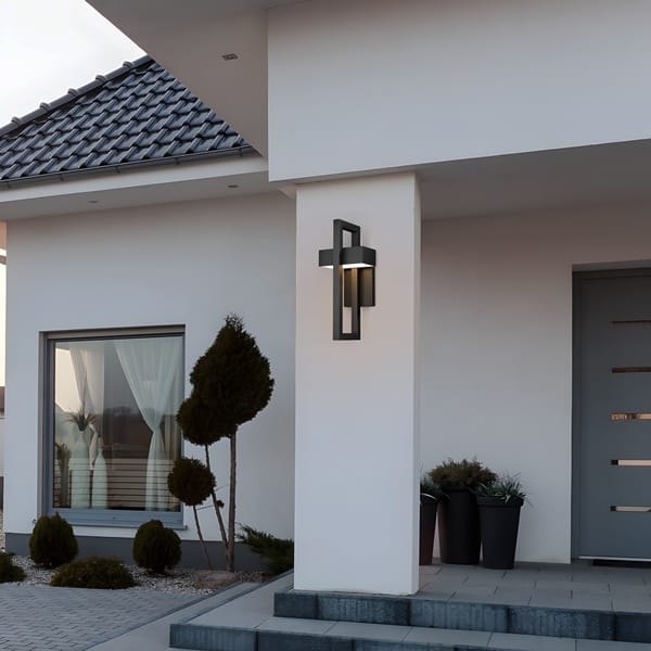 Tekstüre siyah minimal aplik modeli, dikdörtgen çerçevesinden geçen kutu gövdesiyle gri villa cephesinde asılı